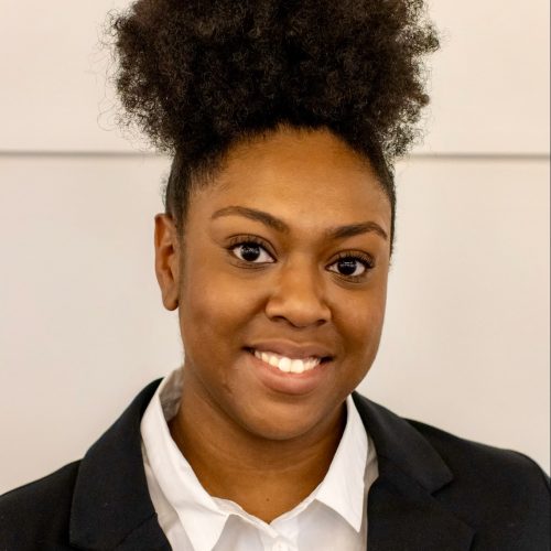 Headshot of Kendall Hall: An African-American woman with her dark brown hair in a bun wearing a white button-up shirt and a black blazer.